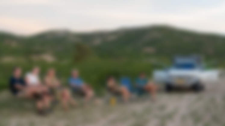 James, Marc, Marie, Mathou, Naomi & Simon sitting watching sunset near ranger camper