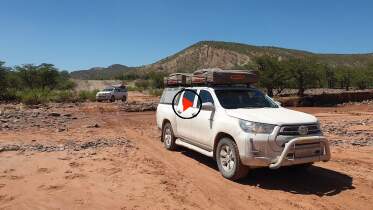 camping cars driving through dry riverbed