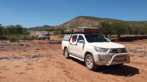 camping cars driving through dry riverbed