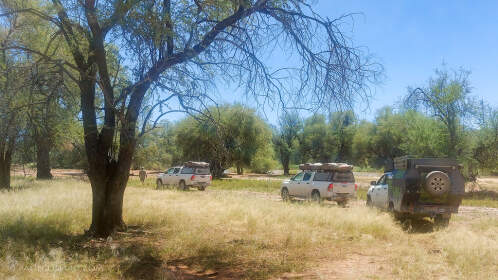 camping cars & ranger camper driving under trees next to river