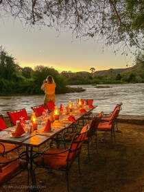 Mathou near candle lighted dinner table at sunset