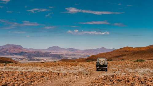 ranger camper on gravel road & hills under clouds