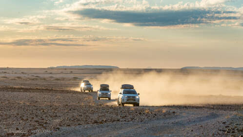 camping cars driving on rocky plain at sunset