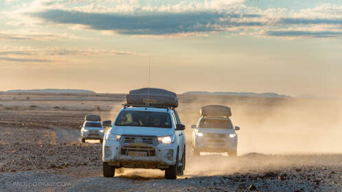 camping cars driving on rocky plain at sunset