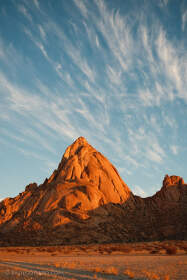 rocky plain with dry grass & red hills at sunset