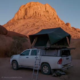 camping car with rooftop tent & red granite rock at sunset