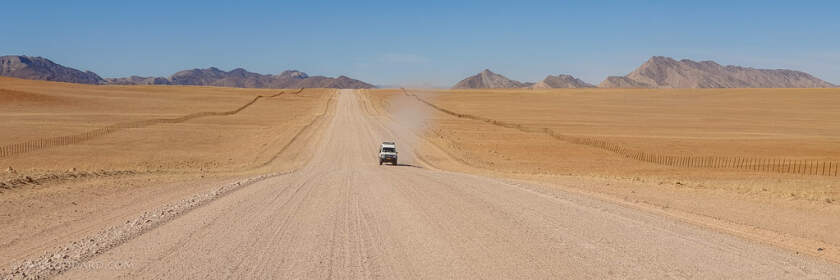 pano - car driving on straight gravel road in arid landscape