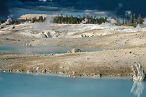 Hot spring in geyser basin under stormy sky