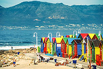 people in front of colorful cabin on beach + mts