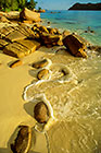 rocks on beach with wave effect + sea + Curieuse island after sunrise