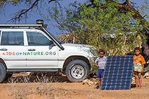 bushman boys + land cruiser with solar panel under tree after rain storm
