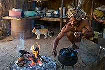 bushman smoking near fire in kitchen