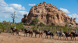 people & guide (West) riding horses near sacred rocks