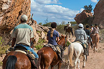 people & guide (West) riding horses near sacred rocks