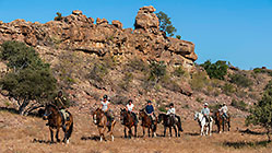 people riding horses near rocky hill