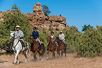 people riding horses near rocky hill