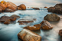 boulders in sea with smooth waves