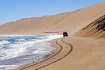 Land Cruiser driving on beach along coast & sand dunes