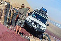Land Cruiser driving on rocks along coast & sand dunes
