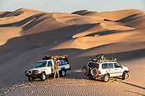 Simons near Land Cruisers on sand dune