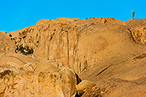 woman standing on top of huge boulder