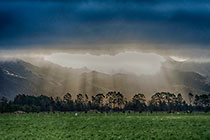 sunset rays through clouds over farmland