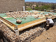 worker filling top gabion baskets with stones before suspended slab