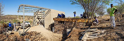 Licius inspecting workers mixing concrete for studio suspended slab over gabion room