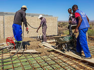 workers pooring concrete on studio suspended slab over gabion room