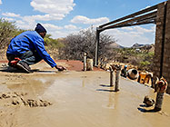 workers levelling concrete on studio suspended slab over gabion room