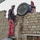 workers filling cement around glass bottles in tyre while building workshop wall