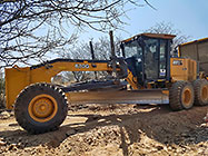 team with grader rescuing 4x4 truck broken down on plot access road