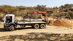 truck with crane dropping bricks in river bed