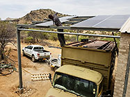 Donald installing solar panel on workshop roof from 4x4 truck