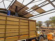 Donald & Sedney installing solar panel on workshop roof from 4x4 truck