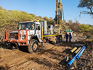 Human truck & workers drilling borehole in riverbed