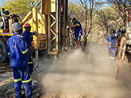 Human truck & workers drilling borehole in riverbed