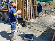 Human truck & workers drilling borehole in riverbed