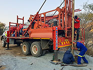Human truck & workers cleaning borehole in riverbed and adding casing