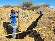 Donald & Sedney measuring level in excavated trenches for house foundation