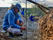 Donald, Paul & Sedney measuring level in excavated trenches for house foundation
