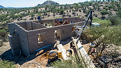 aerial view of 4x4 Unimog with crane installing house roof wooden beams