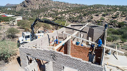 aerial view of 4x4 Unimog with crane installing house roof wooden beams