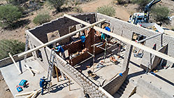aerial view of 4x4 Unimog with crane installing house roof wooden beams
