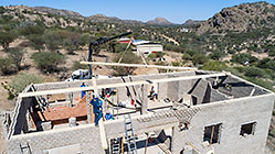aerial view of 4x4 Unimog with crane installing house roof wooden beams