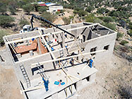 aerial view of 4x4 Unimog with crane installing house roof wooden beams
