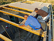 workers installing osd boards over house roof wooden beams
