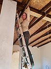 Lisa on ladder sealing roof wooden beams