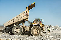 worker & 90 T truck offloading rocks on top of waste pile
