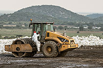 arsenic waste site | worker climbing into roller compactor